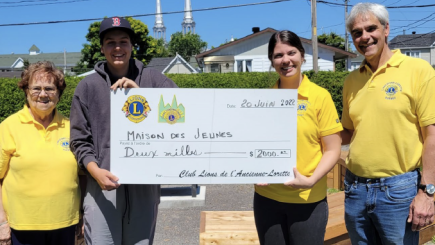 Groupe de 4 personnes, dont 3 portent un chandail jaune avec le logo du Club Lions, tenant tous un chèque à l'ordre de la Maison des jeunes d'une valeur de 2000 $.