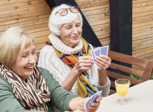 Deux femmes âgées souriantes jouant aux cartes.