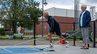 Un homme et une femme âgés jouent au shuffleboard.
