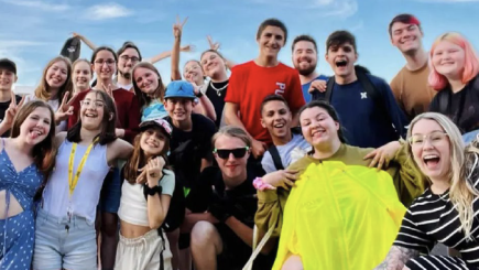 Groupe de jeunes adolescents souriants devant un ciel bleu.