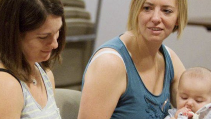 Deux femmes et un bébé dans une salle.